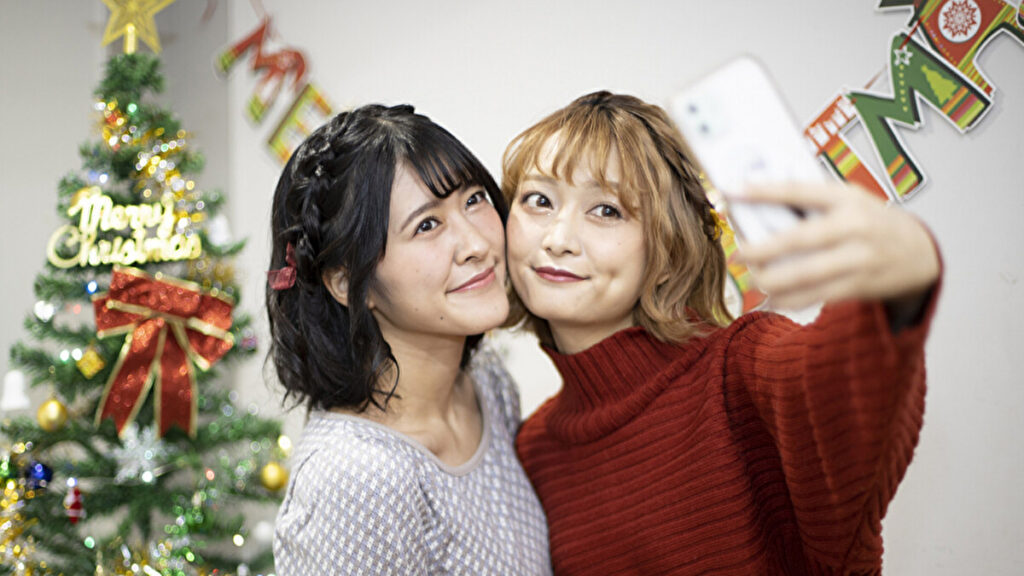 クリスマスツリーの前で写真を撮る二人の女性